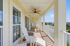 A covered porch with white chairs and a ceiling fan. - Windy Hill Getaway | 3BR at Ocean Marsh (North Myrtle Beach)
