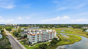 A multi-story hotel with balconies, situated near a river and surrounded by greenery. - Windy Hill Getaway | 3BR at Ocean Marsh (North Myrtle Beach)
