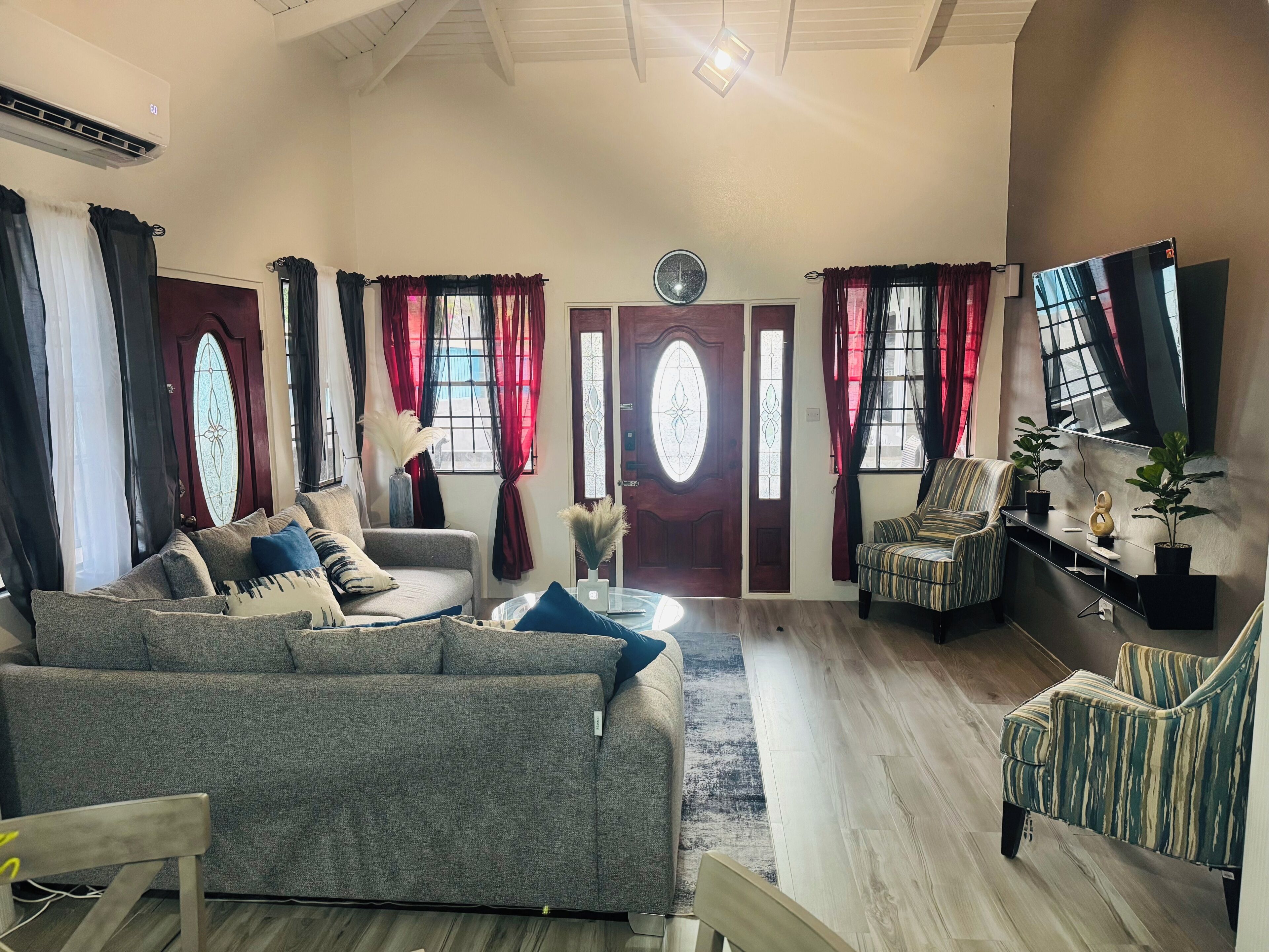 A living room with a grey sofa, a striped armchair, and a small table with potted plants.