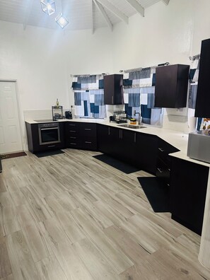 Une cuisine moderne avec des meubles de couleur noire, un four encastré et un plancher en bois clair.