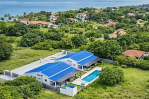 A modern house with a large swimming pool, surrounded by lush greenery and a view of the ocean. - Cozy 2-Bedroom Home · Pool Access · Near Punta Chame Beach (Punta Chame)