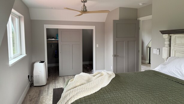 A bedroom with a bed, a ceiling fan, a wardrobe, and a window. - NEW Kenai Cabin with Modern Interior and Cabin Exterior (Soldotna)