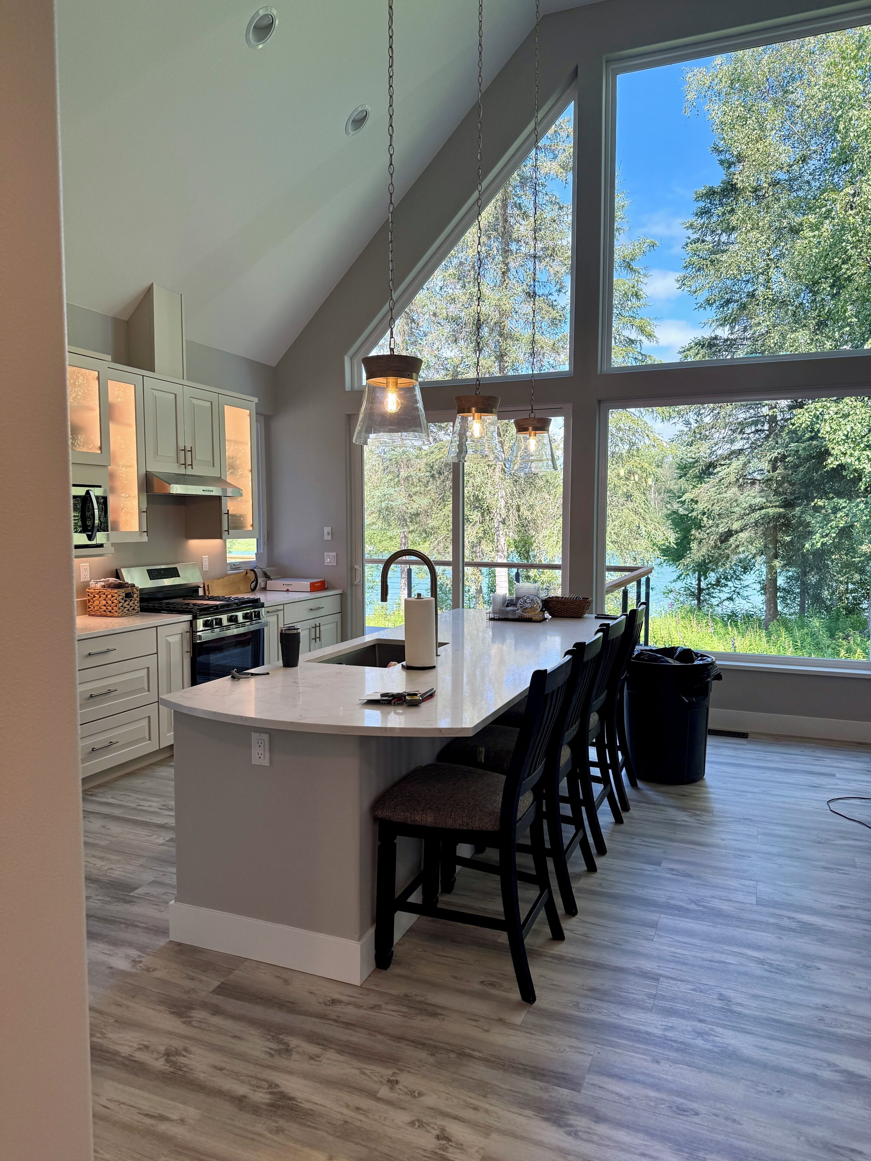A modern kitchen with a large island, white cabinetry, and a view of the outdoors.