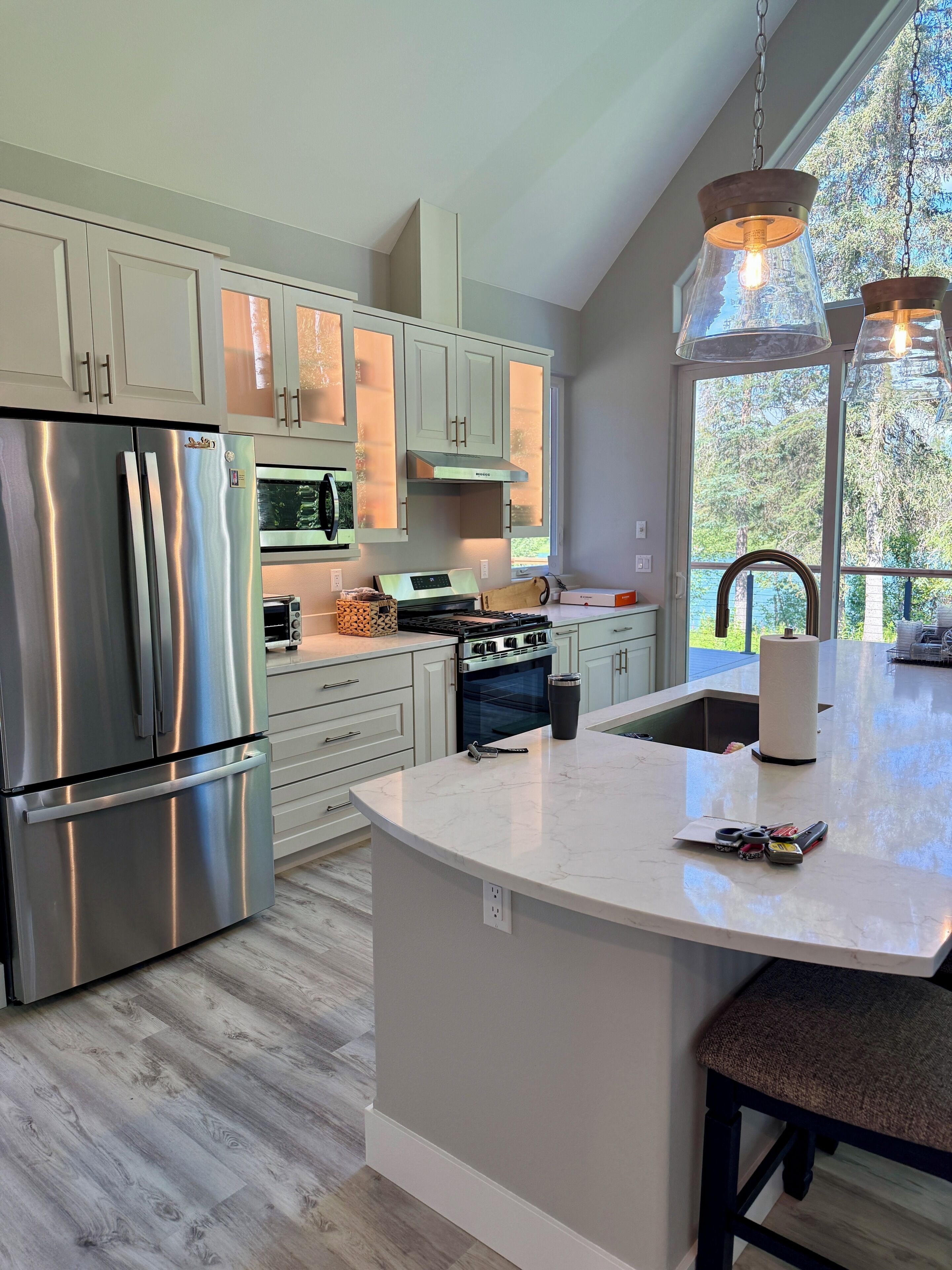A modern kitchen with stainless steel appliances, a large island, and a view of the outdoors.