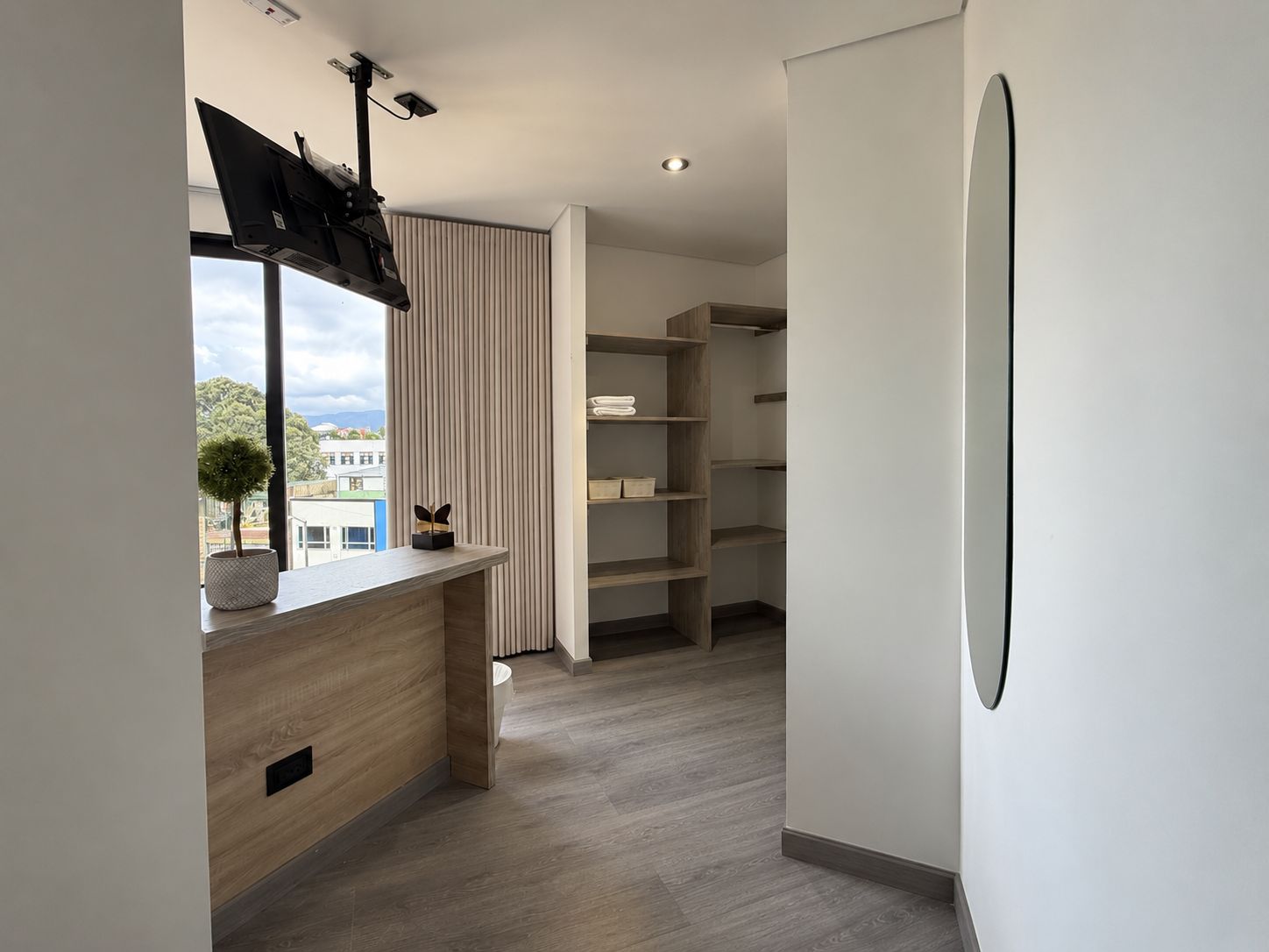Un interior moderno con un escritorio de madera, una estantería empotrada y vistas por una ventana.