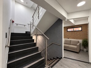 Un interior moderno con una escalera, un sofá y una planta en maceta.