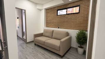 Un interior moderno con un sofá color beige, una planta en maceta y una pared de ladrillo.