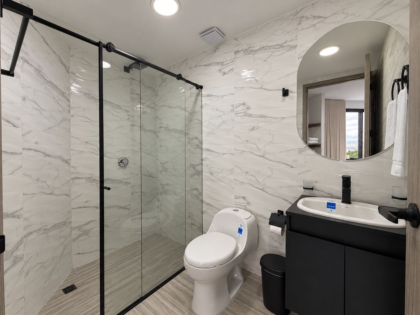 Un bagno moderno con doccia vetrata, un WC bianco e un mobile lavabo nero con specchio.