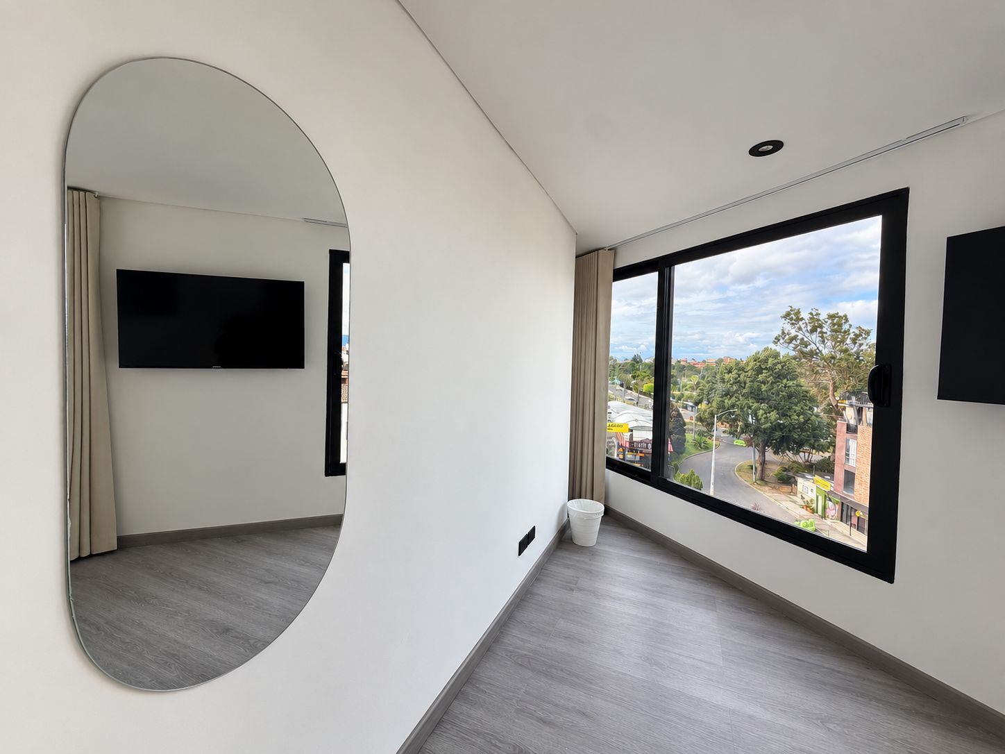Una habitación moderna con una pared curva, un ventanal grande y un televisor de pantalla plana.