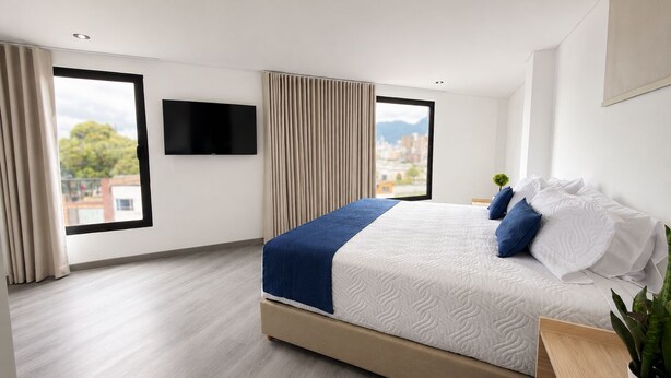 Una habitación de hotel moderna con una cama grande, televisor de pantalla plana y vista a la ciudad.