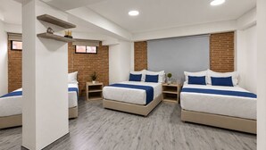 Una habitación de hotel moderna con dos camas, una pared decorada con ladrillo y un ventanal grande.
