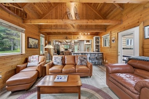 Ein gemütliches Blockhaus-Interieur mit Ledersofas, einem Holzesstzimmerstisch und einer Küchenzeile.