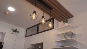 Eine moderne Küche mit Pendelleuchten, weißen Schränken und einem Holzbalken an der Decke.