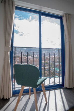 A room with a large window, a chair, and a view of a cityscape. - Modern apartment with 2 sleeping areas (Cusco)