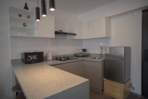 A modern kitchen with white cabinets, a stainless steel refrigerator, a microwave, and a gas stove. - Modern apartment with 2 sleeping areas (Cusco)