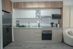 Eine moderne Küche mit einbauendem Backofen, Mikrowelle und Kaffeemaschine auf der Arbeitsfläche.