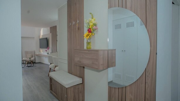 Ein modernes Schlafzimmer mit Einbauschrank, Nachttisch, Bank und Spiegel.