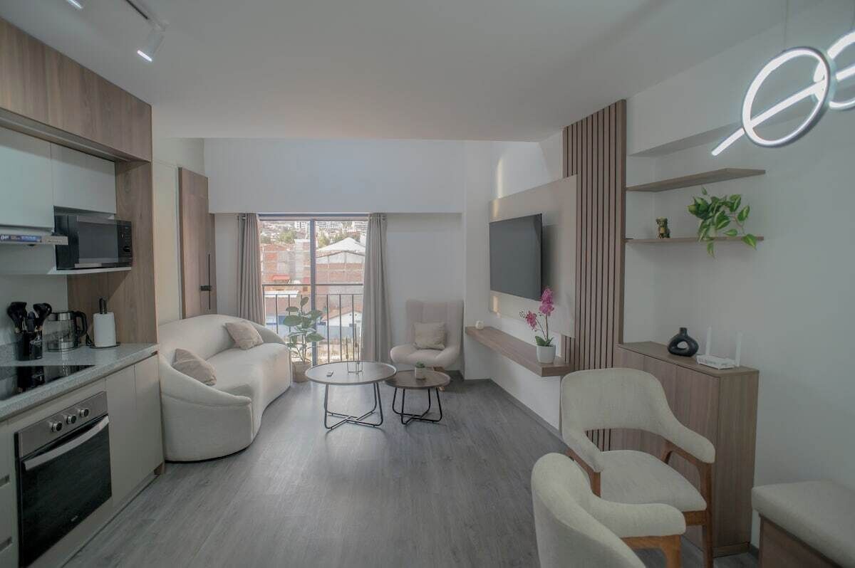 A modern living room with a sofa, armchairs, a coffee table, and a TV.