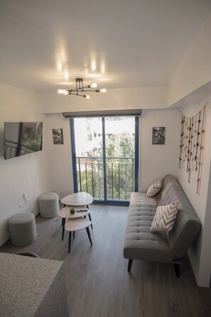 A modern living room with a grey sofa, a round table, and a balcony with a view. - Modern studio near Qorikancha (Cusco)