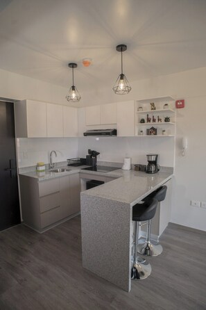 A modern kitchen with a central island, stainless steel appliances, and pendant lighting. - Modern studio near Qorikancha (Cusco)