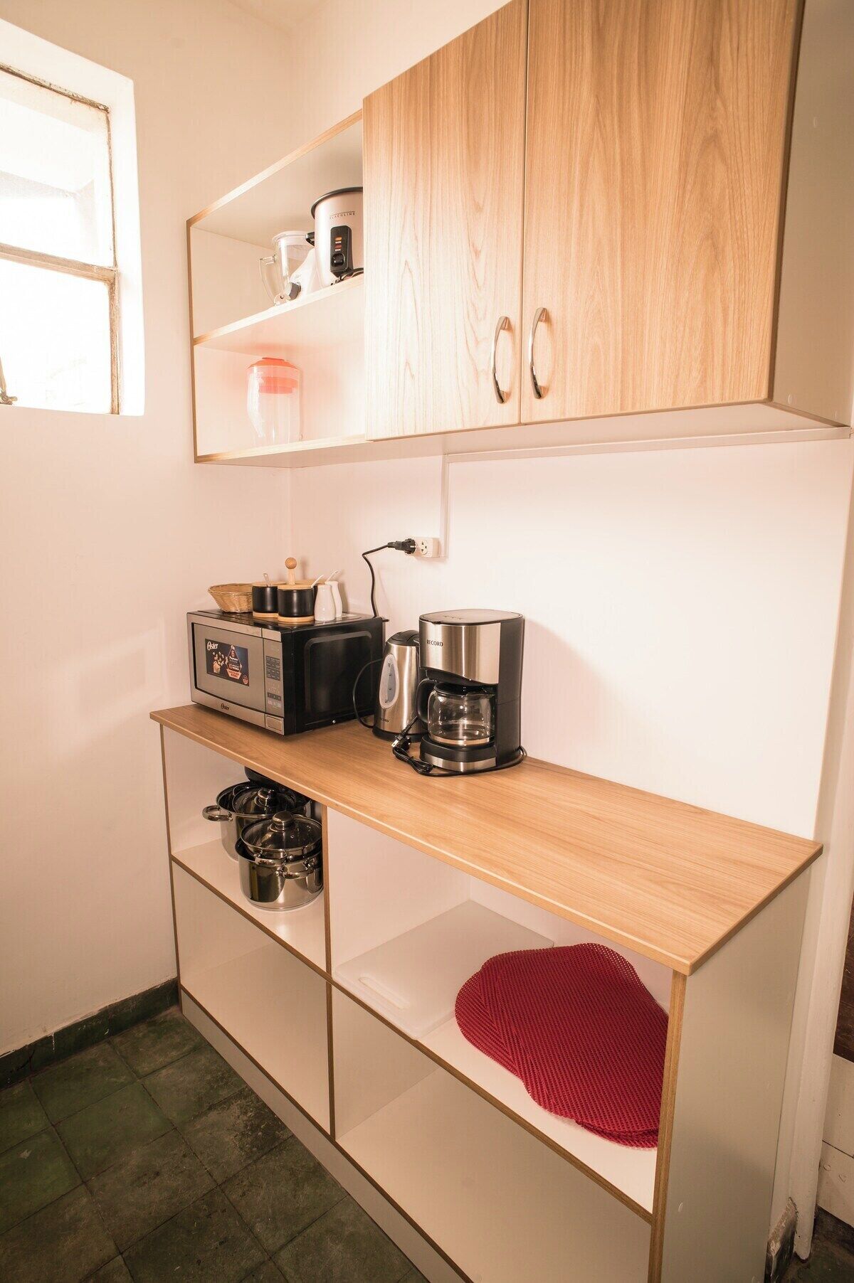 A compact kitchenette with a coffee maker, a toaster, and a microwave on a wooden countertop.