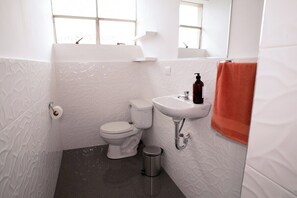 A bathroom with a toilet, sink, and trash bin. - Spacious vintage apartment in Zarumilla (Cusco)