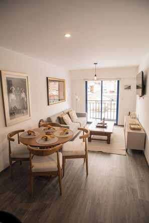 A modern living room with a dining table, sofa, and TV. - Spacious family apartment near the center (Cusco)