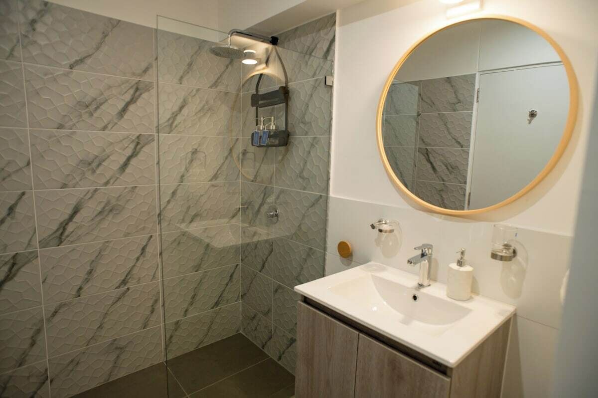 A bathroom with a shower, a sink, a mirror, and a toilet.