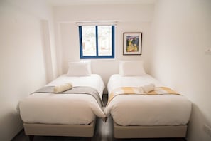 A twin room with two beds, a window with blue frames, and a picture on the wall. - Spacious family apartment near the center (Cusco)