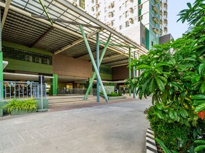A covered outdoor area with a metal roof structure, a gated entrance, and a building with multiple floors in the background. - Oak & Sage | 2BR | King Bed | IT Park | Fast Wi-Fi (Cebu City)