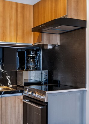 A modern kitchen with wooden cabinets, a stainless steel range, a built-in oven, and a microwave. - Oak & Sage | 2BR | King Bed | IT Park | Fast Wi-Fi (Cebu City)