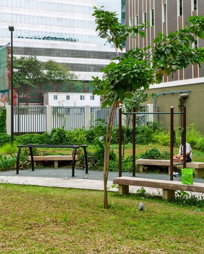 Een park met bankjes, een speeltuin en een gebouw op de achtergrond.