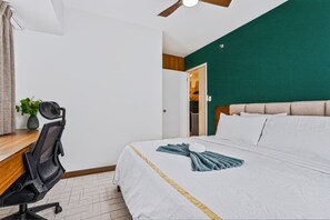 Een hotelkamer met een bed, een bureau, een stoel en een plafondventilator.