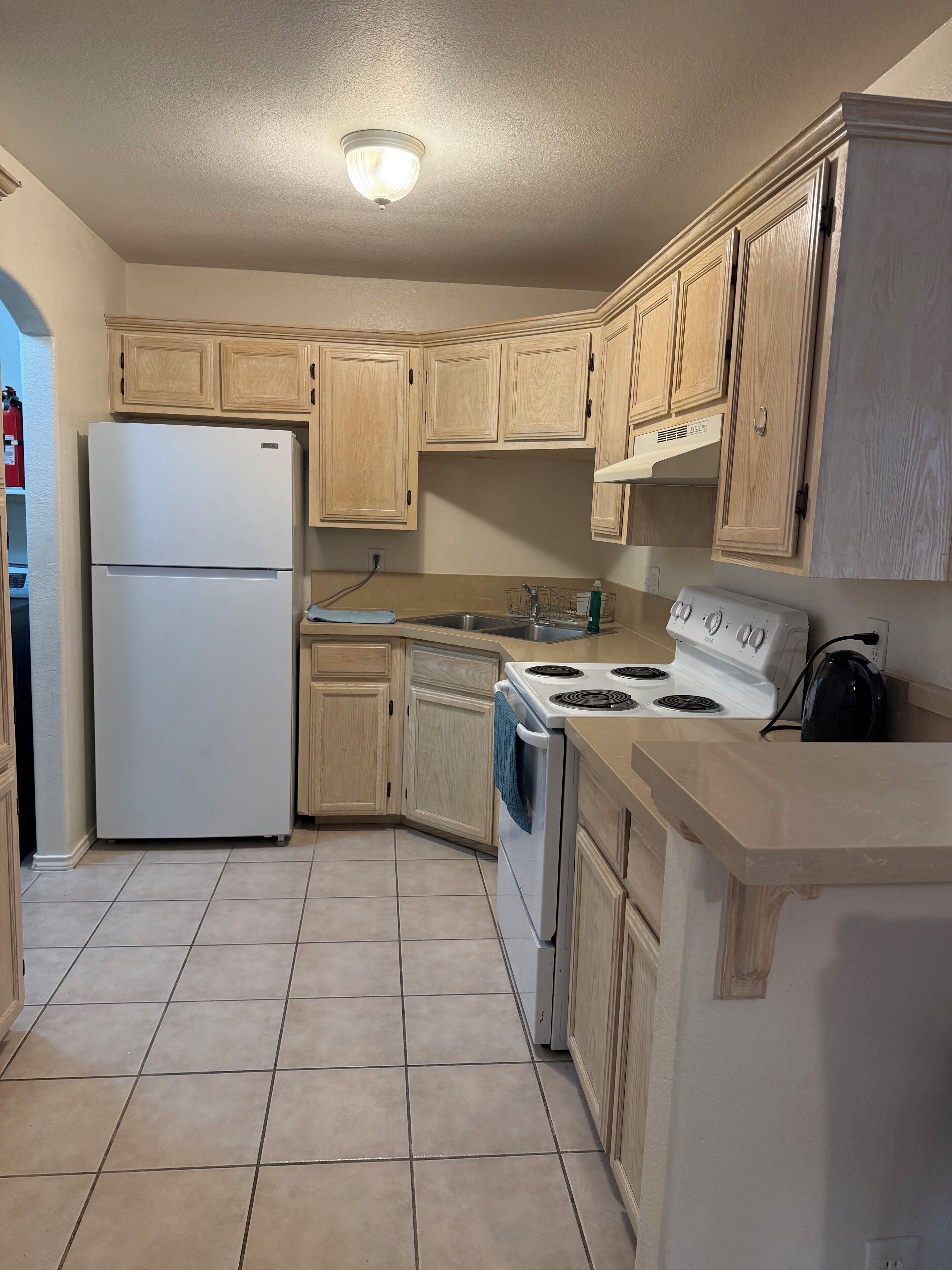 A kitchen with wooden cabinets, a white refrigerator, a stove, and a sink.
