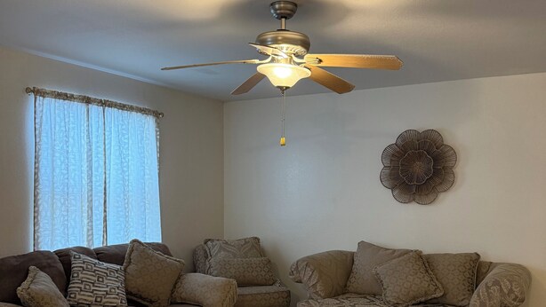 A living room with a sectional sofa, a ceiling fan, and a decorative wall piece. - 2-bedroom apartment in welcoming Harlingen with AC comfort (Harlingen)