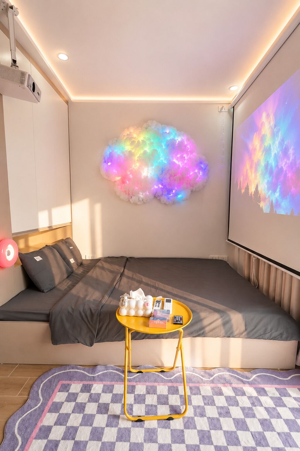 A cozy room with a sofa, a small table, a projector screen, and a cloud-shaped light installation.