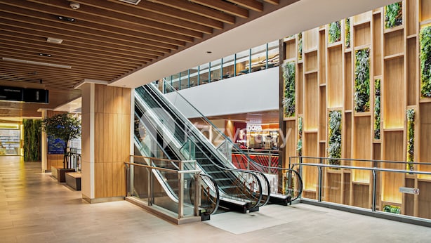 A modern interior with an escalator, wooden paneling, and a glass railing.