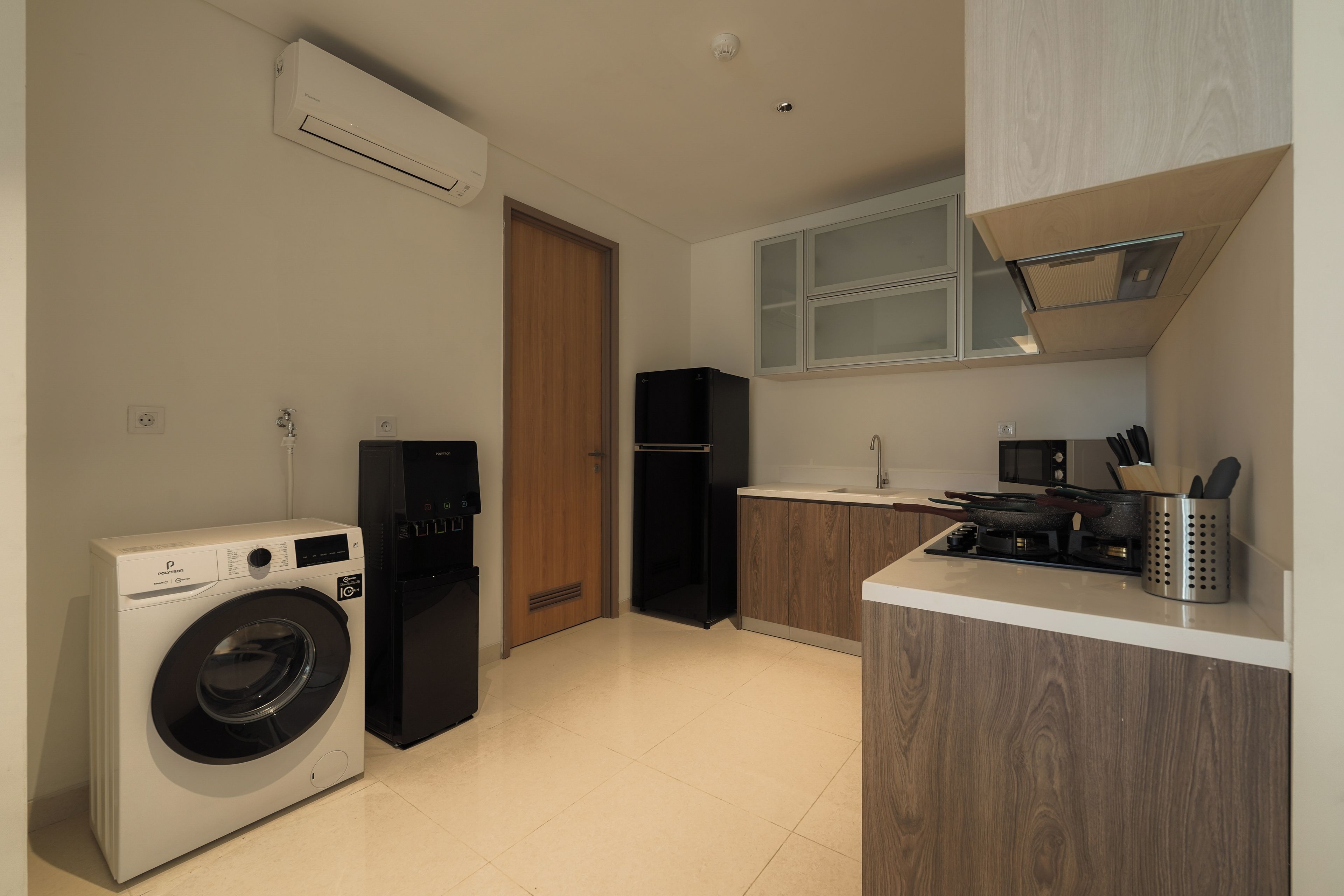 A compact kitchen with a washing machine, a refrigerator, and a microwave.