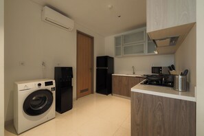 A compact kitchen with a washing machine, a refrigerator, and a microwave.