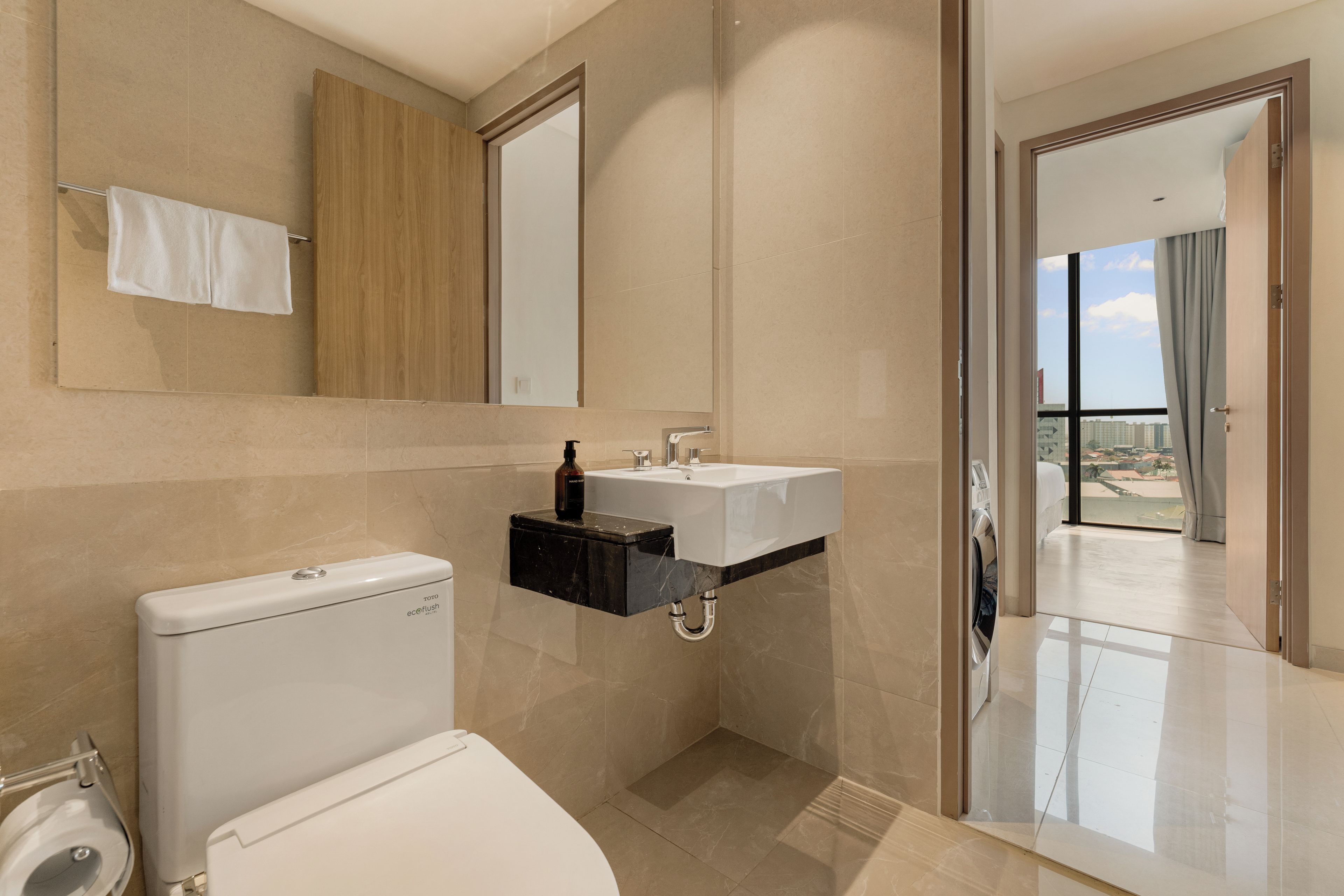 A modern bathroom with a toilet, sink, and mirror.