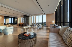 A spacious living area with a large window, a round coffee table, and modern furniture.