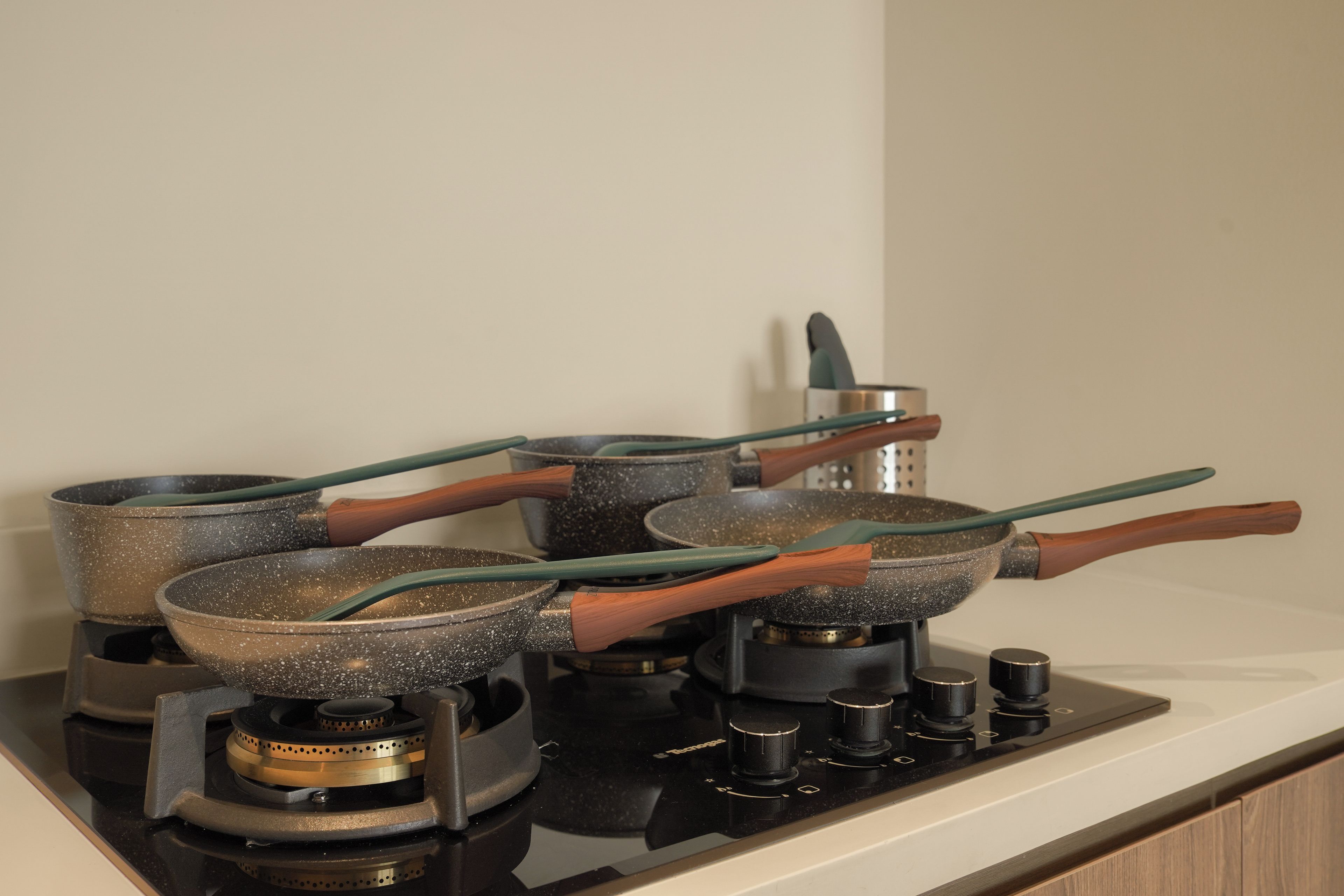 A kitchen with a gas stove, multiple pots, and pans with wooden handles.