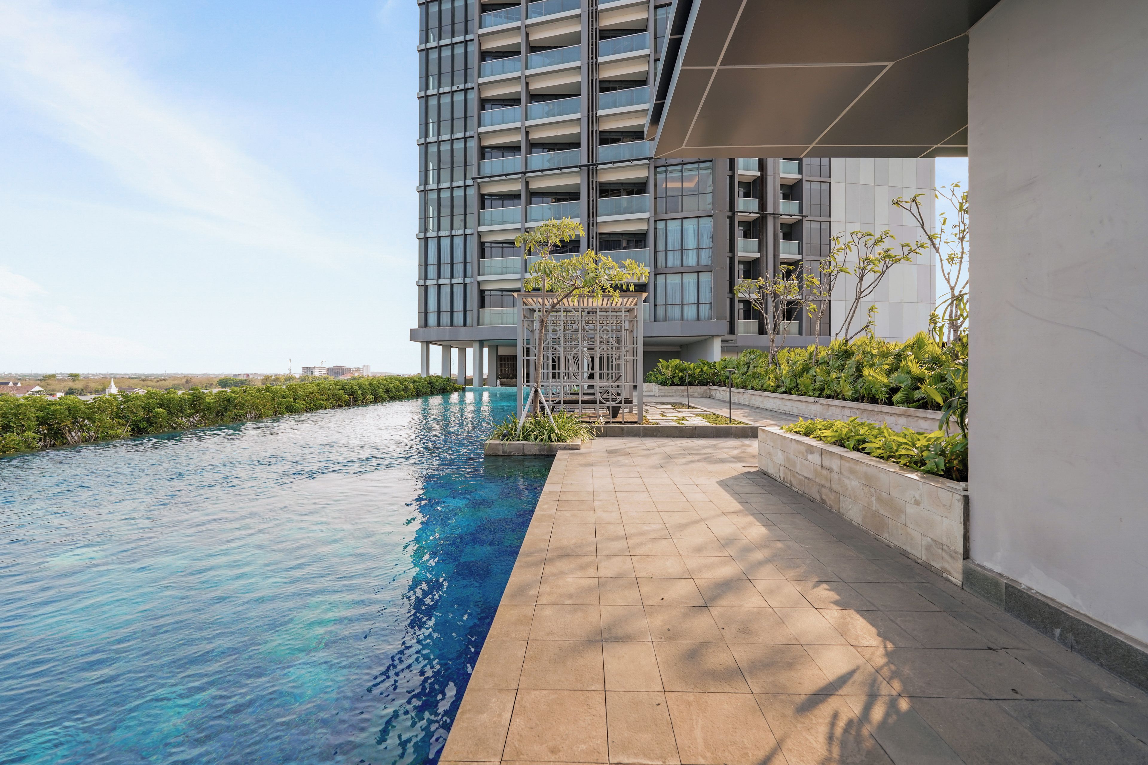 A modern building with a swimming pool and a landscaped area with plants.