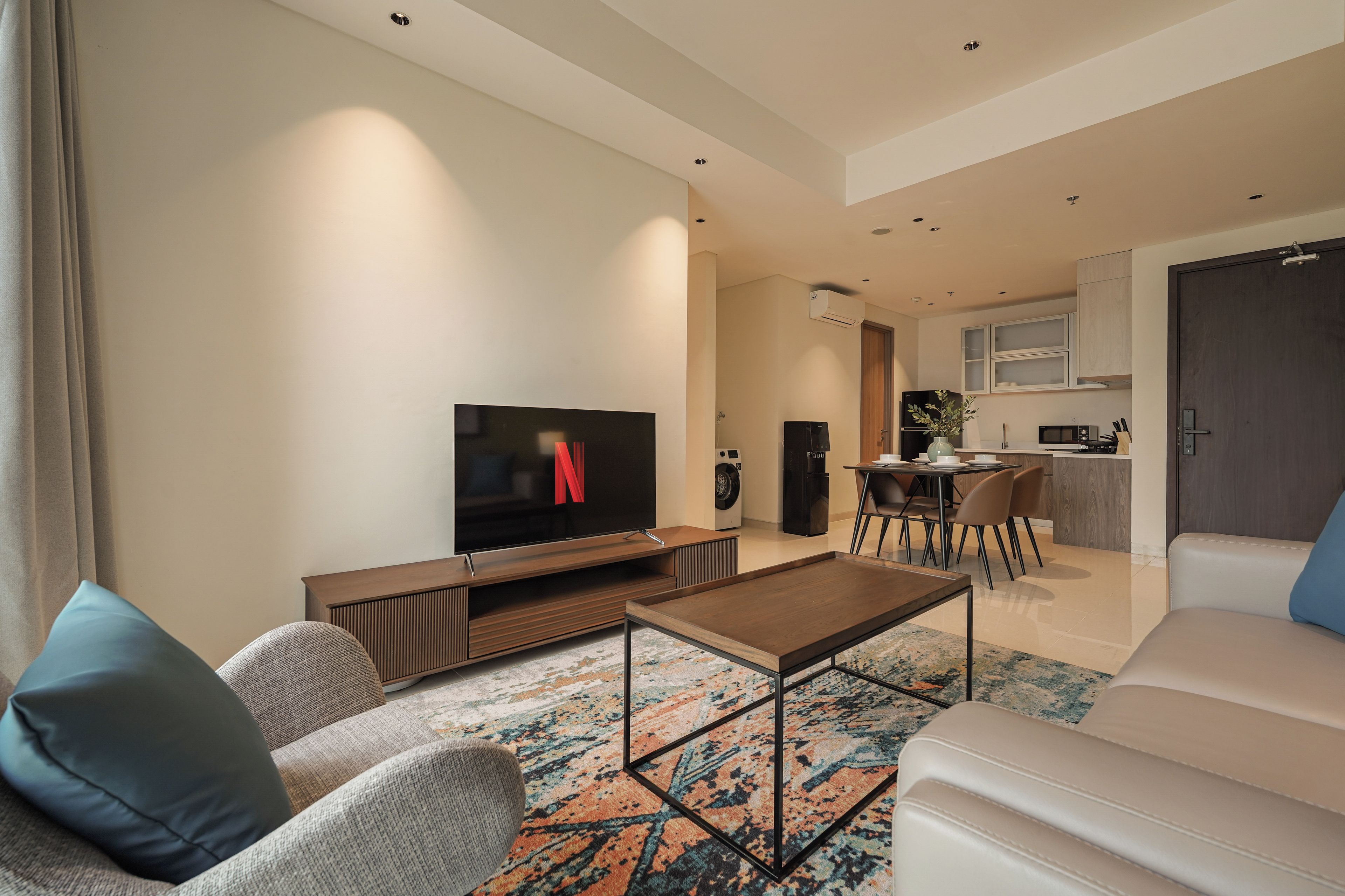Ein modernes Wohnzimmer mit Fernseher, Couchtisch und Sitzgelegenheiten.