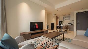 Ein modernes Wohnzimmer mit Fernseher, Couchtisch und Sitzgelegenheiten.