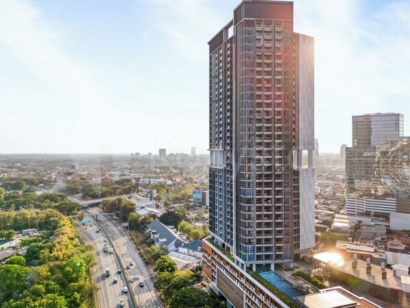 A high-rise building with multiple floors, surrounded by a cityscape with roads and greenery.
