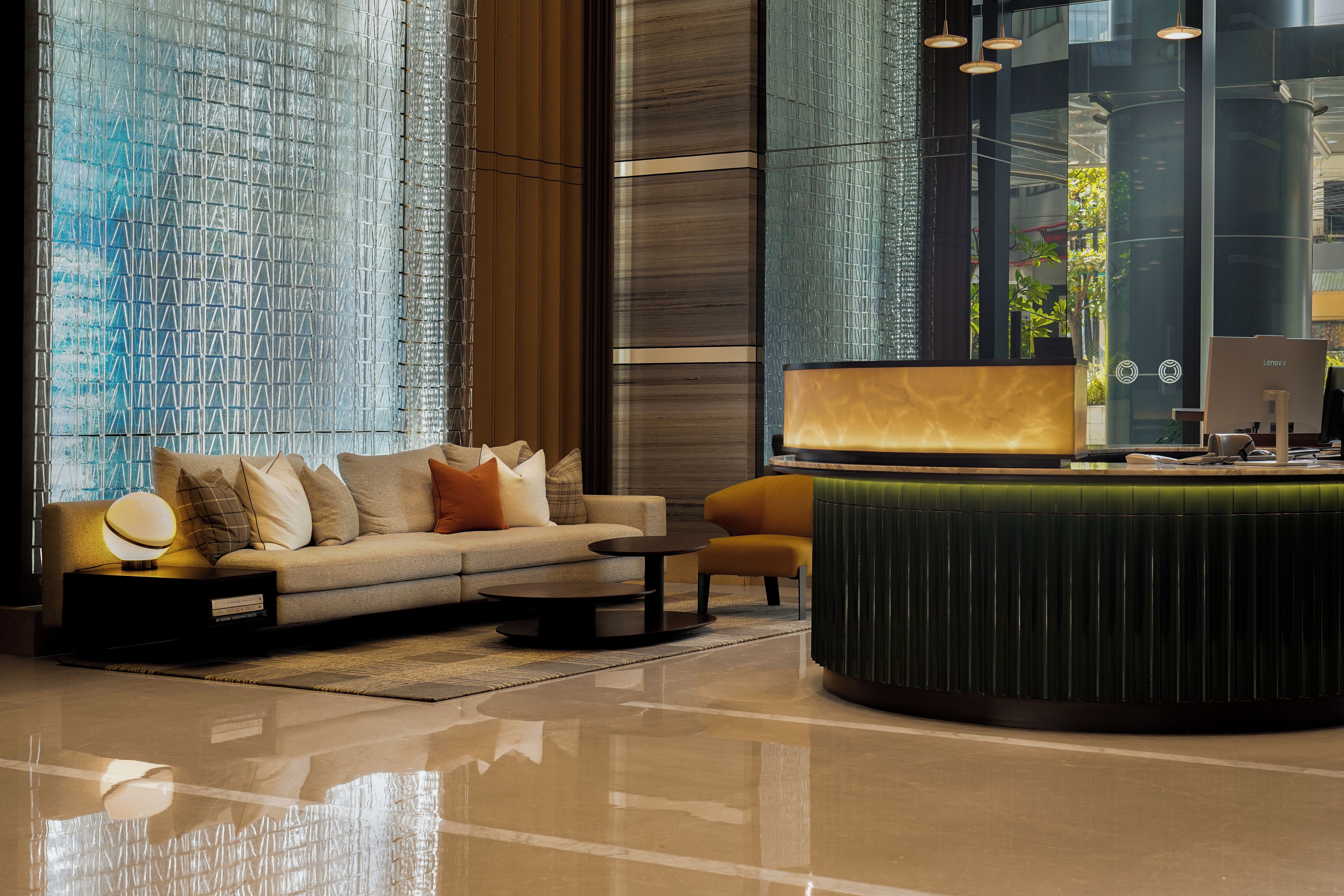 A modern lobby with a sofa, a round table, and a reception desk.