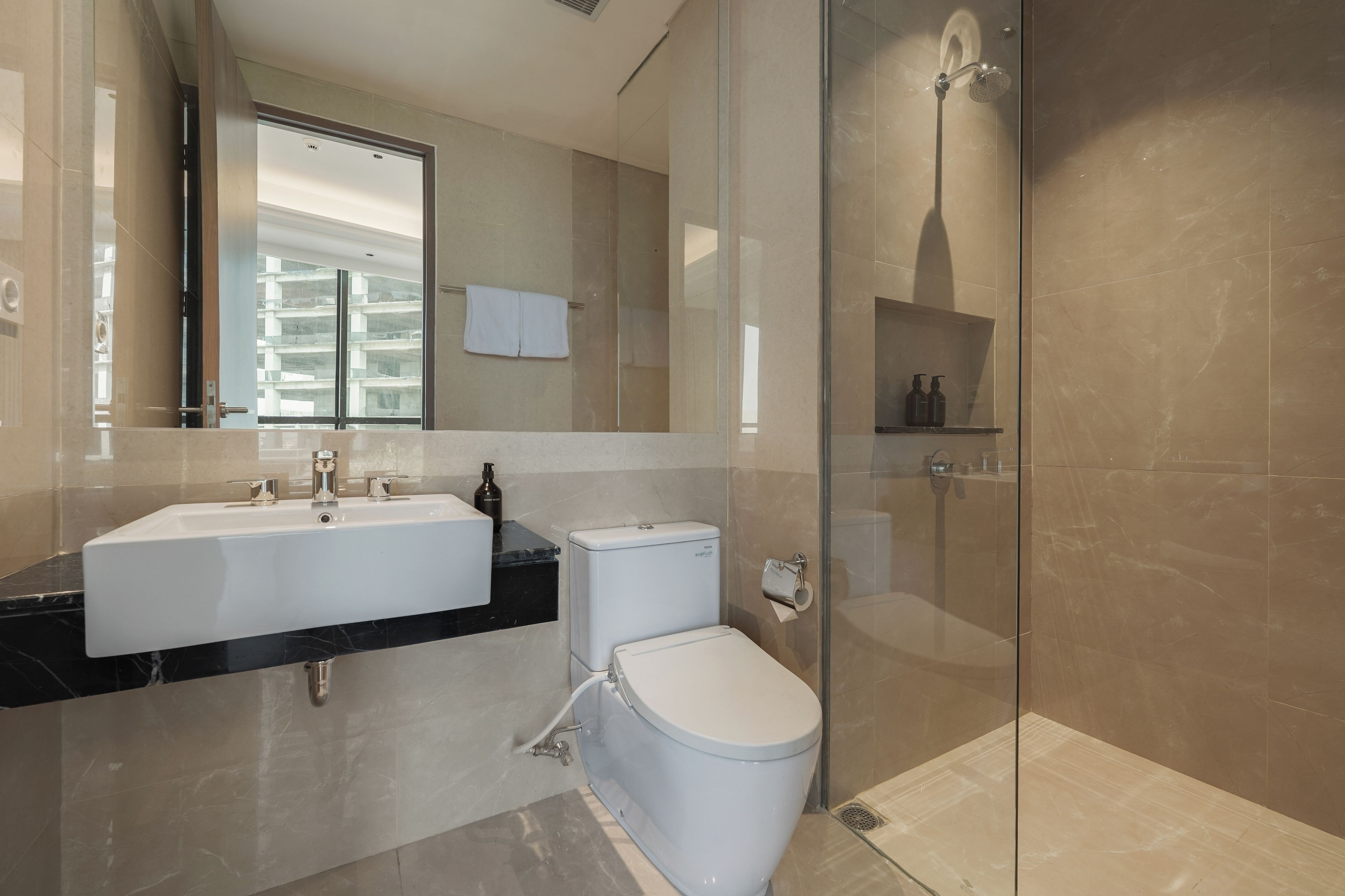 A modern bathroom with a glass shower enclosure, a white toilet, and a dual sink vanity.