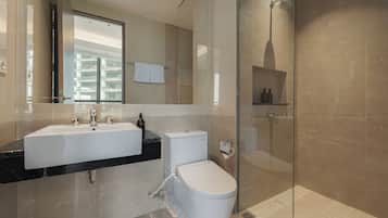 A modern bathroom with a glass shower enclosure, a white toilet, and a dual sink vanity.