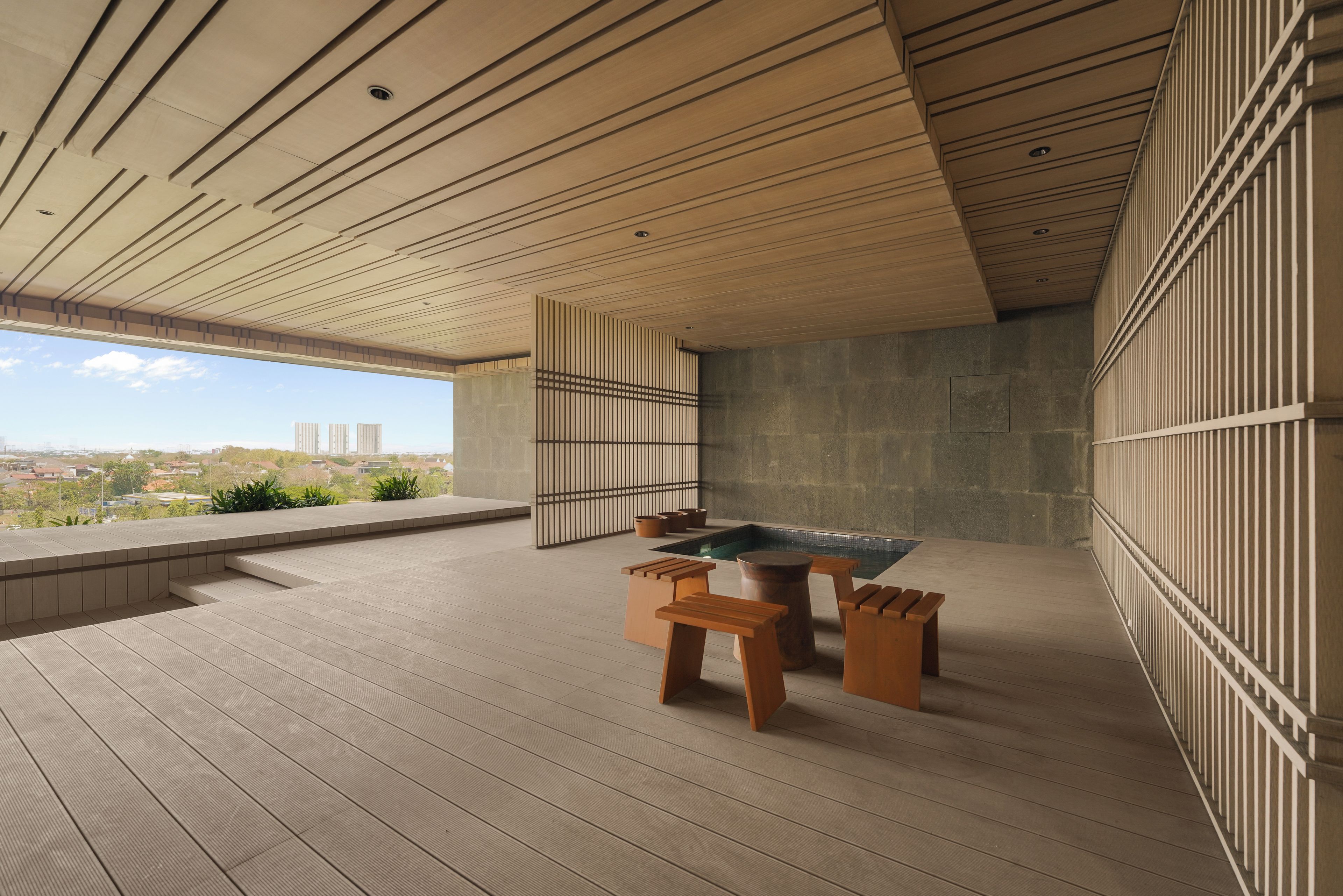 Un interior moderno con piscina, muebles de madera y vistas a la ciudad.